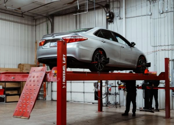 GLG_Alignment_600x433 silver car up on red lift - with two technicians working on alignment