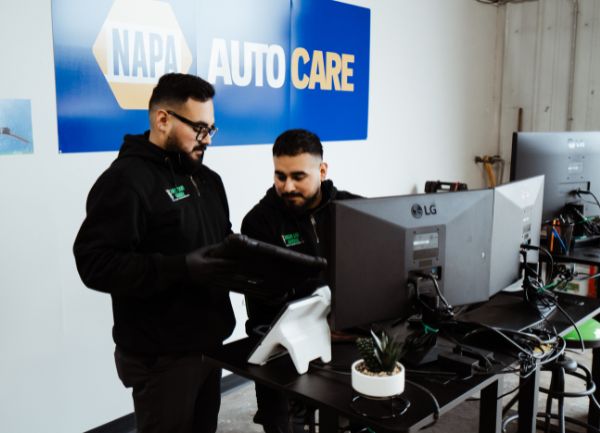 Green Light Garage Diagnostics_600x433 two technicians at desk with multiple computer monitors - looking at a hand held diagnostic tablet